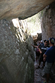 People examining the walls of a narrow stone cleft